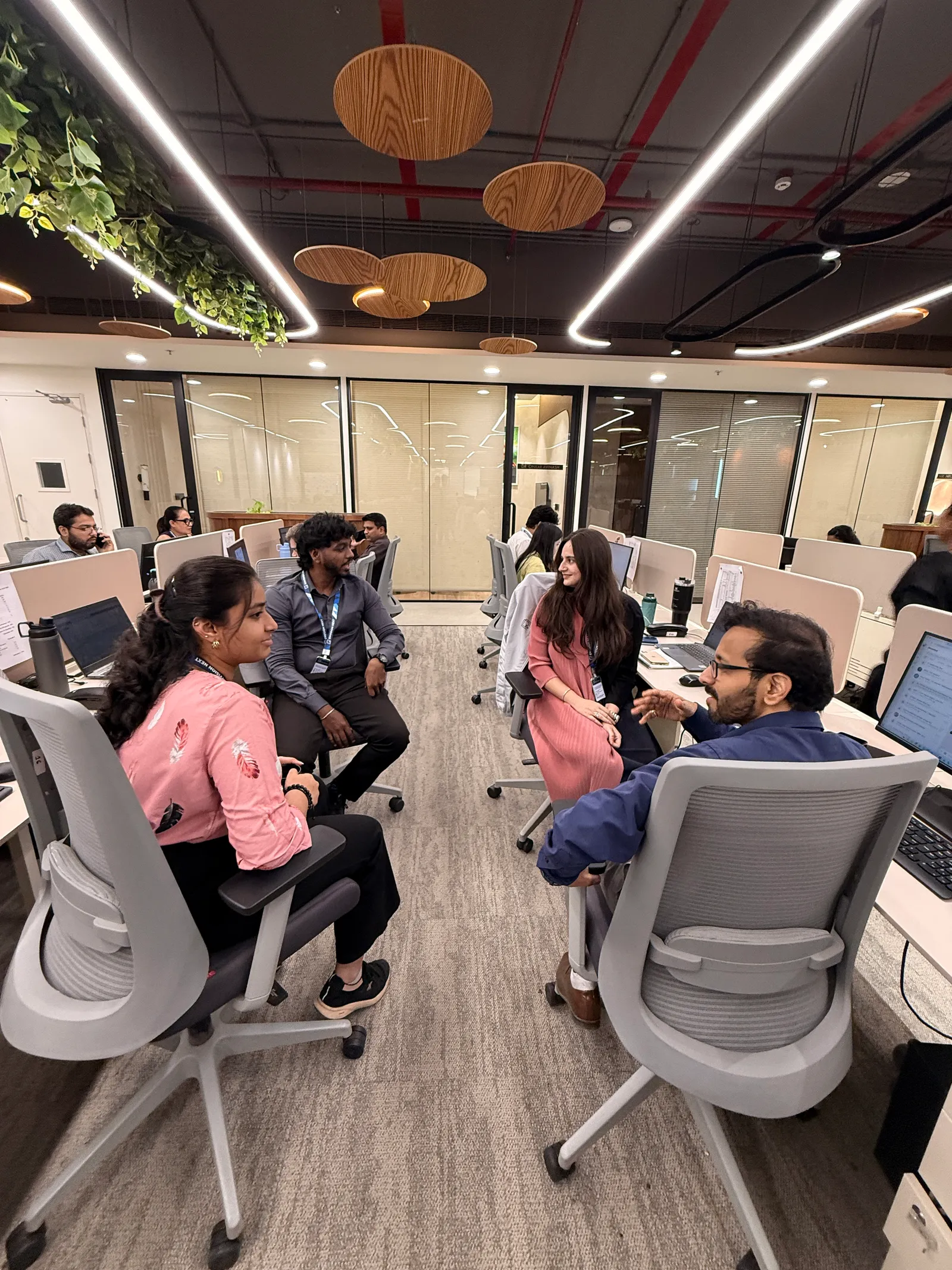 Colleagues in discussion at their desks on the open-plan floor